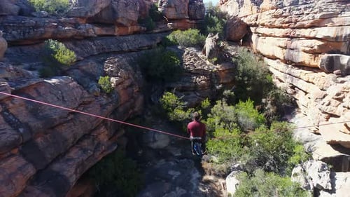 Young Adult Balances on Highline Above Rocky Terrain