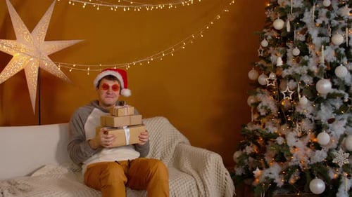Man on Couch with Christmas Gifts Indoors