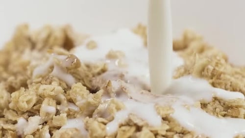 Milk Pouring Over Crunchy Breakfast Cereal Close Up