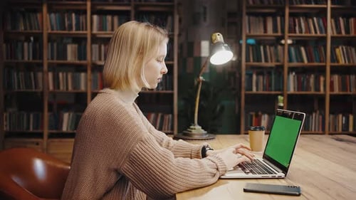 Tracking Shot of Young Caucasian Woman Student Typing on Laptop with Green Chroma Key Screen
