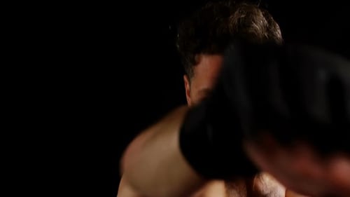 Intense Man Boxing with Gloves in Dark Studio
