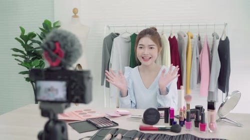 Una bloguera de belleza presenta cosméticos de belleza sentada frente a la cámara frontal para grabar un vídeo