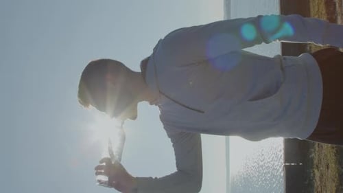Young Man Drinks Water After Exercise By Ocean