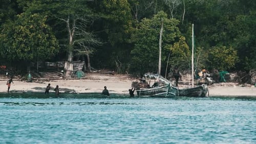 Los lugareños de un pueblo pesquero africano descargan el barco de pesca en dhow frente a la costa