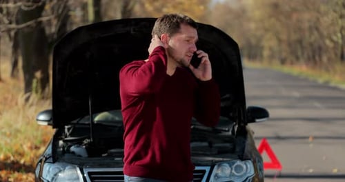 Man Talking on Phone in Front of Broken Car
