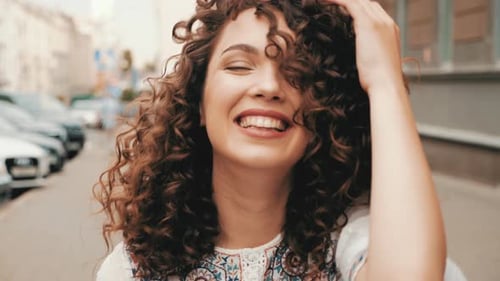 Cheerful Woman Posing with Curly Hair on City Street