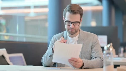 Casual Man Reading Documents in Office