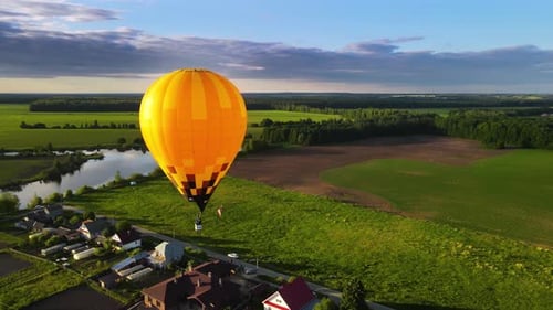 Yellow balloon with balloonist above field glows in dazzling rays of setting sun