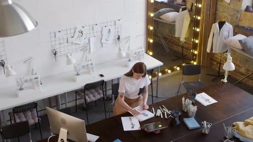 Fashion Designer Sketching Clothing Designs in Studio