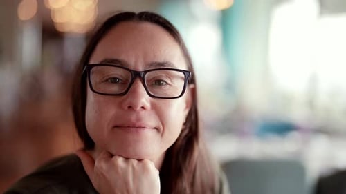 Woman in Glasses Smiling Calmly Indoors