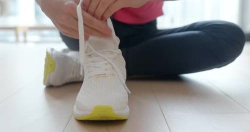 Woman Tying Shoelaces of Athletic Shoes