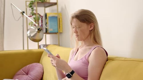 Woman Using Phone Relaxing on Sofa Indoors