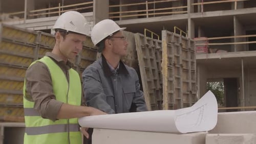 Engineers Reviewing Construction Plans at Building Site