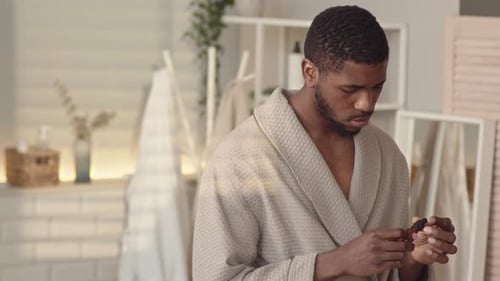 Man Applies Facial Oil in Bathroom