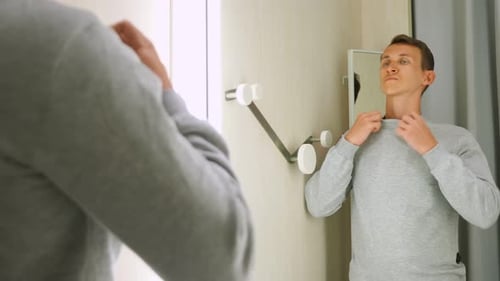 Schöner Mann in einem grauen Sweatshirt vor einem Umkleideraumspiegel