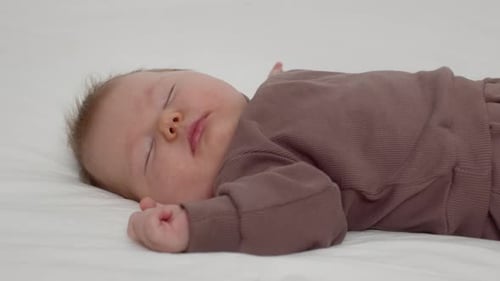 Sleeping Baby on White Sheet in Pajamas