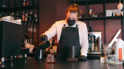 Female Barista in Protective Mask Preparing Coffee Pouring Hot Drink Into Cup in Cafe