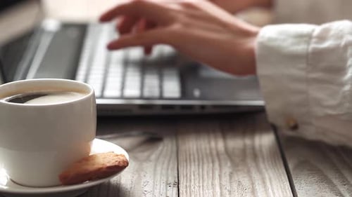 Woman Typing on Laptop with Coffee and Cookie