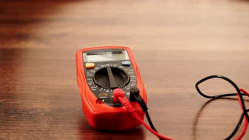 Red Multimeter on Table with Cables