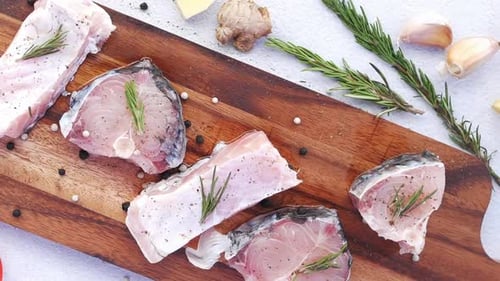 Fresh Fish Steaks with Rosemary on Wooden Board