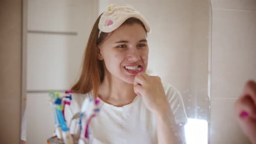 Woman Brushing Teeth in Bathroom Mirror Close Up