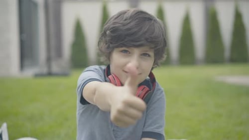 Smiling Boy Giving Thumbs-Up in Garden