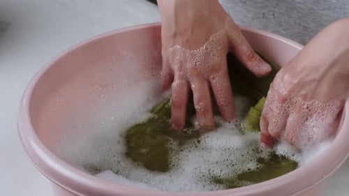 Washing Green Towel in Basin with Froth and Washing Powder Closeup Using Detergent for Spoiled Dirty