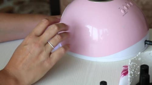 A Woman Dries Her Nails In An Ultraviolet Lamp. She Gives Herself A Manicure