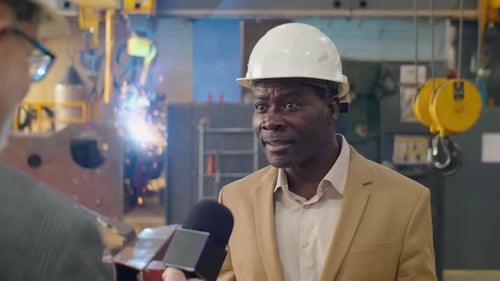 Un ingénieur d'usine afro-américain interviewe un journaliste de télévision