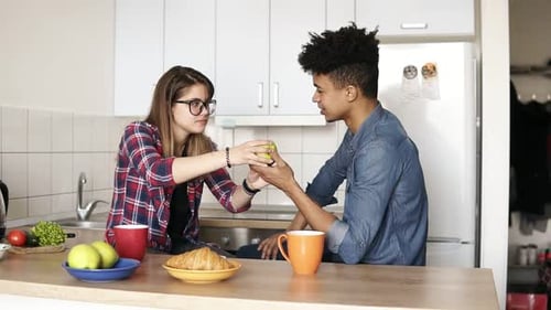 Young Couple Sharing an Apple in Kitchen
