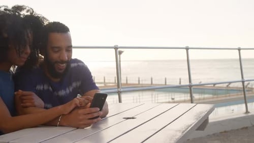 Couple using mobile phone in the beach