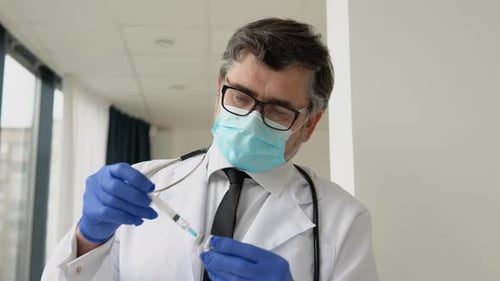 Doctor Holds a Syringe and Vaccine Bottle at the Hospital