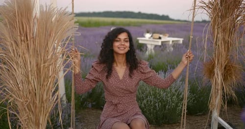 Young Indian Woman Sitting on a Decorated Swing in Lavender Field