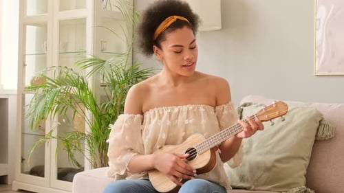 African american woman playing on ukulele practicing music hobby guitar and sing