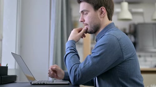 Young Adult Thoughtful Work on Laptop Computer Indoors