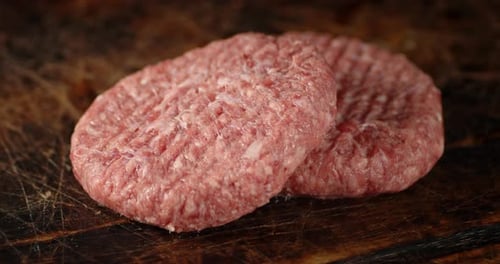 Raw Burger of Fresh Beef Rotates on the Table.