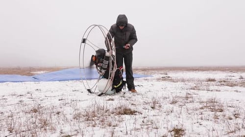 Man Starts To Work a Propeller Motor Engine of the Paramotor Paraglider