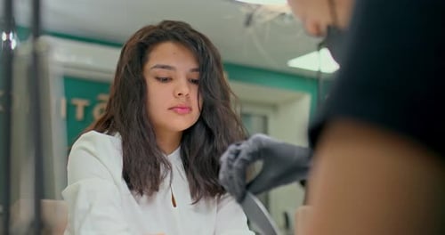 Beautiful Girl with Oriental Appearance Sits on a Manicure Procedure in a Modern Manicure Studio