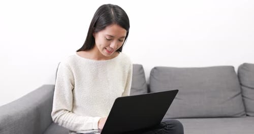 Woman Using Laptop Computer at Home on Sofa