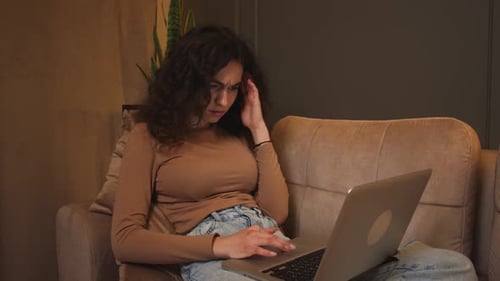 Young Woman Using Laptop at Home on Couch