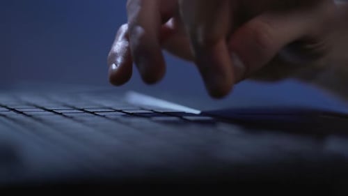 Hände einer Person, die bis spät in die Nacht am Laptop arbeitet, um die Projektfrist einzuhalten