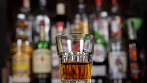 A Closeup of a Glass of Whiskey Slowly Rotates in the Bar