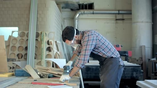 Bearded Carpenter Working with Electric Planer on Wooden Plank in Workshop