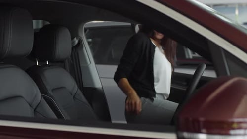 Beautiful Woman Sitting in New Car in Auto Dealership Showroom