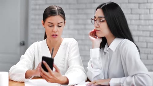 Two Young Women Discuss Business in Modern Office