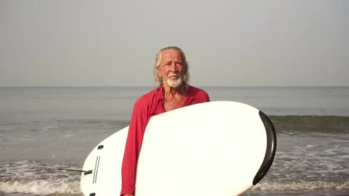 Active Adult Old Male Surfer on the Background of the Sea