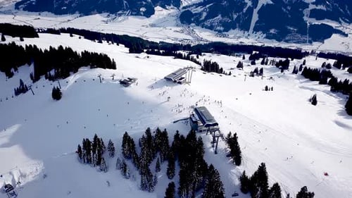 Aerial view of ski resort with people snowboarding down the hill. Stock footage. Flying over the ski