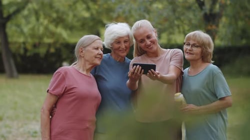 Female Fitness Coach Taking Selfie with Senior Women in Park