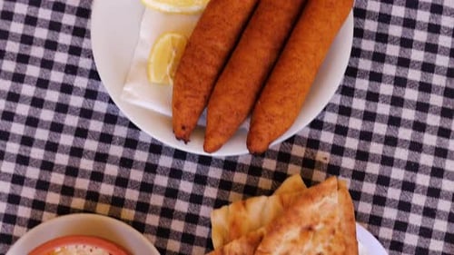 Blick von oben über frisch gebackenes Fladenbrot auf Teller auf Tisch gestapelt zusammen mit anderen Gerichten mit Dips