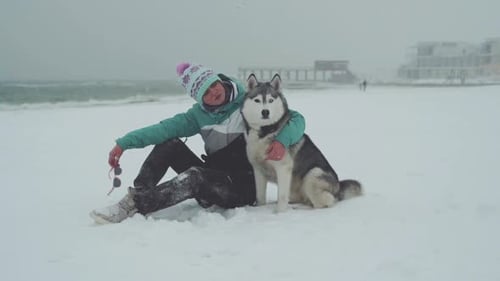 Young Female Playing and Runing with Siberian Husky Dog on the Beach at Snow Storm Slow Motion